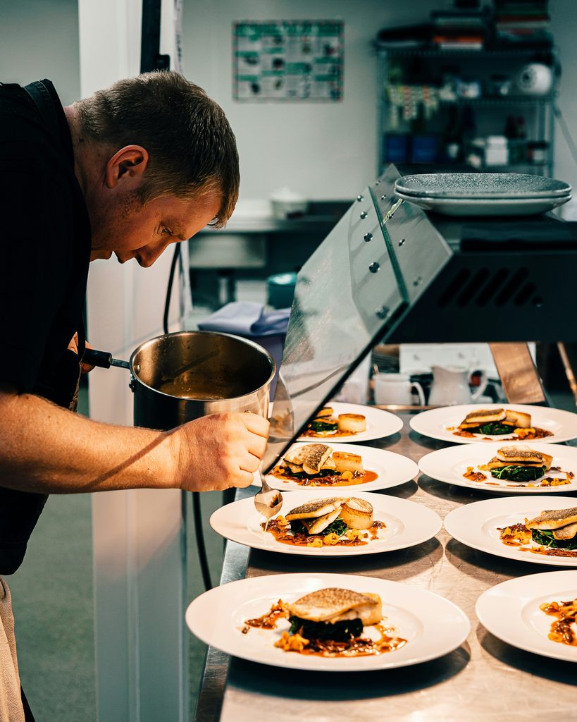 Chef dando los últimos toques a los platos en la mesa de pase del restaurante